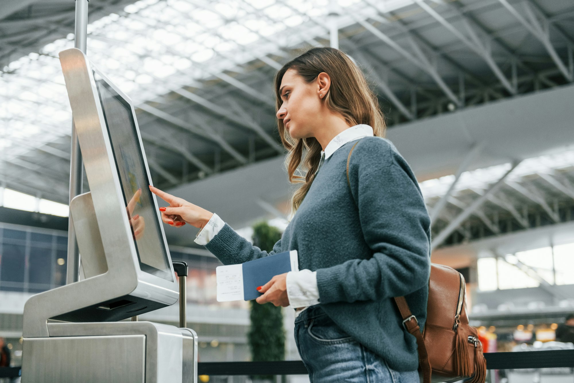 Using terminal. Young female tourist is in the airport at daytime